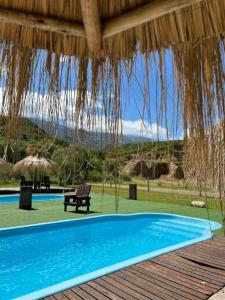 einen Pool mit einem Strohschirm und einer Bank in der Unterkunft La Herradura Village in Merlo