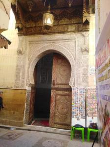 フェズにあるriad zahraの大きな木製のドアのある建物の入口