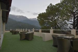 a balcony with chairs and tables and a view of mountains at The Royal Castle AC Centralized in Dharamshala