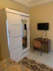 um quarto com uma cama, uma secretária e uma televisão em Résidence Hadja 02 em Dakar