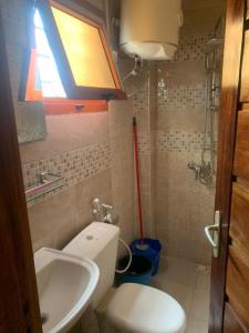 La salle de bains est pourvue de toilettes blanches et d'un lavabo. dans l'établissement Résidence Hadja 02, à Dakar