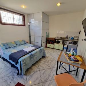 a bedroom with a bed and a table and a kitchen at Trenzin de Aconchego Apto no Centro Histórico in Ouro Preto