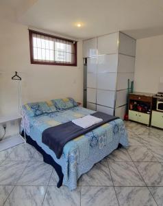 a bedroom with a bed with a blue blanket on it at Trenzin de Aconchego Apto no Centro Histórico in Ouro Preto