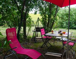 a table and chairs with an umbrella and a grill at Maison charmante à Aignes avec jardin et barbecue in Aignes