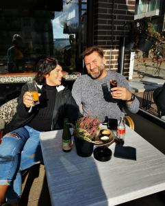 un homme et une femme assis à une table avec des boissons dans l'établissement HHVDK aan zee, à Oostduinkerke