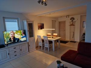ein Wohnzimmer mit einem TV und einem Esstisch in der Unterkunft Haus Sandra Glowe in Glowe