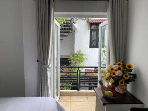 1 Schlafzimmer mit einer Tür und einem Balkon mit Blumen in der Unterkunft Ngọc Sinh Homestay in Hoi An