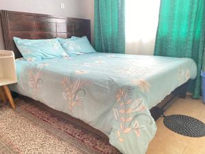 a bed with a blue comforter with flowers on it at The Cream Loft in Eldoret