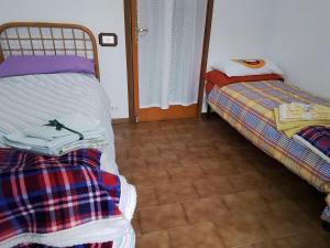 sypialnia z 2 łóżkami i podłogą wyłożoną kafelkami w obiekcie Casamarche w mieście Montalto Dora