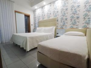 a bedroom with two beds and a wall with flowers at Hotel Gaby in Rimini