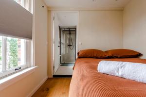 een slaapkamer met een oranje bed en een raam bij Railway Forge Loft in Haarlem
