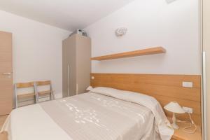 1 dormitorio con cama blanca y cabecero de madera en Golfo Aranci - Gli Orizzonti 26, en Golfo Aranci