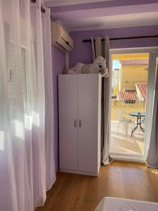 Rooms Florie في بيشيشي: غرفة أرجوانية مع خزانة بيضاء وطاولة