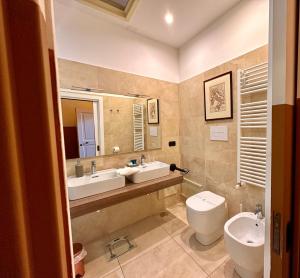 a bathroom with two sinks and a toilet and a mirror at Casa Santangelo Suites in Salerno