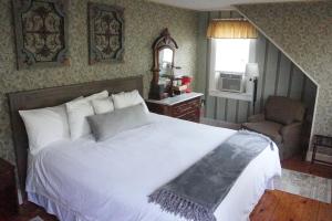 a bedroom with a large white bed and a chair at The Frogtown Inn in Canadensis