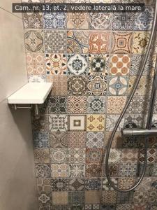 a bathroom with a tile wall with a shower at Beach Rooms Roberta in Mamaia +161 photos