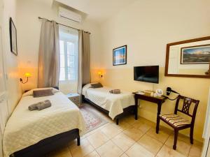 a room with two beds and a desk and a television at The Maltese Sun in Sliema