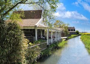 une maison au bord d'une rivière dans l'établissement Idyllisch en knus huisje met prachtige veranda., à Oterleek