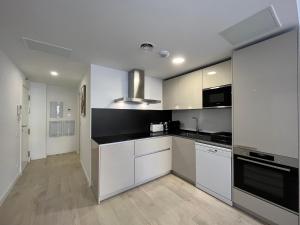 uma cozinha com armários brancos e bancadas pretas em Apartamento Horta de Santa Maria em Cambrils