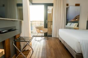 um quarto com uma cama, uma cadeira e uma janela em Novotel Criciuma em Criciúma