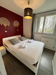 um quarto com uma cama branca e uma parede vermelha em Ceibo YourHostHelper em Caen