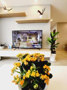 een woonkamer met een tv en een vaas met bloemen bij Michael Apartment Scenic Valley in Ho Chi Minh-stad