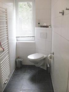 a white bathroom with a toilet and a window at Pension TimeOut in Kassel
