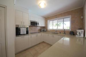 a large kitchen with white cabinets and a window at Agave Gardens in Palm-Eagle Beach