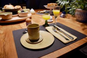 einen Holztisch mit einem Teller und einer Tasse und einer Weingläser in der Unterkunft B&B Bergdal in Gits