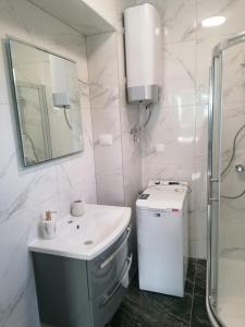 Baño blanco con lavabo y espejo en Apartments and Rooms Tomas, en Podstrana