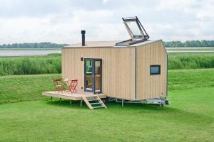 a tiny house with a table and chairs in a field at Tiny House Pioneer 2 - Hooksiel im Wangerland in Wangerland