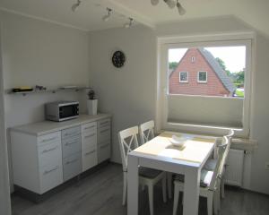 eine Küche mit einem Tisch, einer Mikrowelle und einem Fenster in der Unterkunft FeWo-Möwenpaar-Norden-Norddeich in Norden