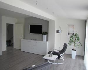 sala de estar con TV, silla y mesa en FeWo-Möwenpaar-Norden-Norddeich en Norden