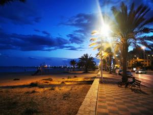 a person sitting on a bench on a beach at night at Apartamento a 5 minutos distancia de playa en Puerto de Sagunto -Full Apartment -120m2 in Puerto de Sagunto