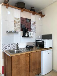 eine Küche mit einer Spüle und einer Mikrowelle in der Unterkunft ARETI Sea View Mountain Cottage in AmigdhalokeFálion