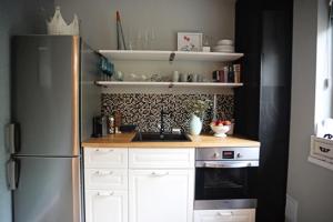 una cucina con frigorifero in acciaio inossidabile e mobili bianchi di Moft Loft. Lovely, comfy apartment. a Cluj-Napoca