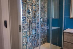 uma casa de banho com uma cabina de duche em vidro com azulejos azuis em La Casa di Eolo em Licata