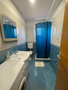 a bathroom with a sink and a blue shower curtain at Apartments Santa Marija in Dol
