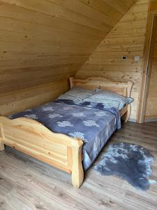 a bed in a wooden room with a wooden floor at Leśny Domek in Brenna