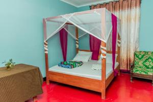 a bedroom with a canopy bed and a table at Royal Wonders Hotel in Moshi