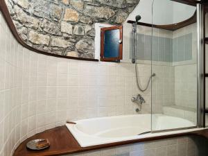 een badkamer met een bad en een douche met een spiegel bij La Tuga appartamento stile marinaro sul mare in Imperia