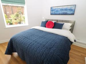 een slaapkamer met een bed met een blauw dekbed en een raam bij "Happy Valley Boutique Accomodation" Hotel Quality, Offering Free Parking in Hebden Bridge