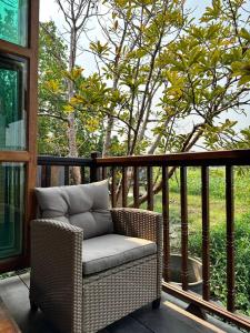 a wicker chair sitting on a porch with a tree at RuenKijja in Ban Kroen +61 photos