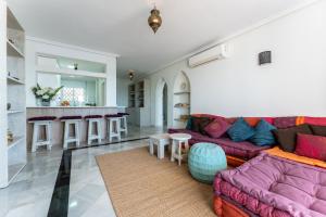 Oasis la Cala في ميخاس: غرفة معيشة مع أريكة أرجوانية ومطبخ