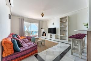 sala de estar con sofá púrpura y TV en Oasis la Cala en Mijas