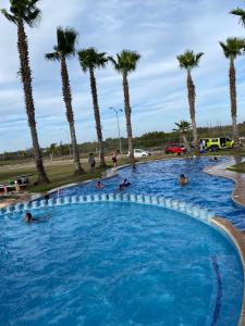 Personnes nageant dans une piscine bordée de palmiers dans l'établissement Hermosa Casa Villas de Cortes en Altata, à Culiacán