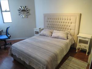 een slaapkamer met een bed, een stoel en een spiegel bij Cómodo y elegante departamento in Santiago