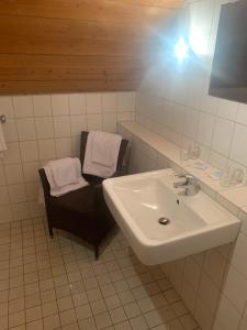 bagno con lavandino, specchio e sedia di Hotel Maien a Todtmoos