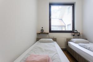 twee bedden in een kleine kamer met een raam bij BIG PIPE apartment in Ljubljana