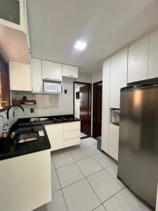 a kitchen with white cabinets and a stainless steel refrigerator at Winterville flat 307 in Gravatá